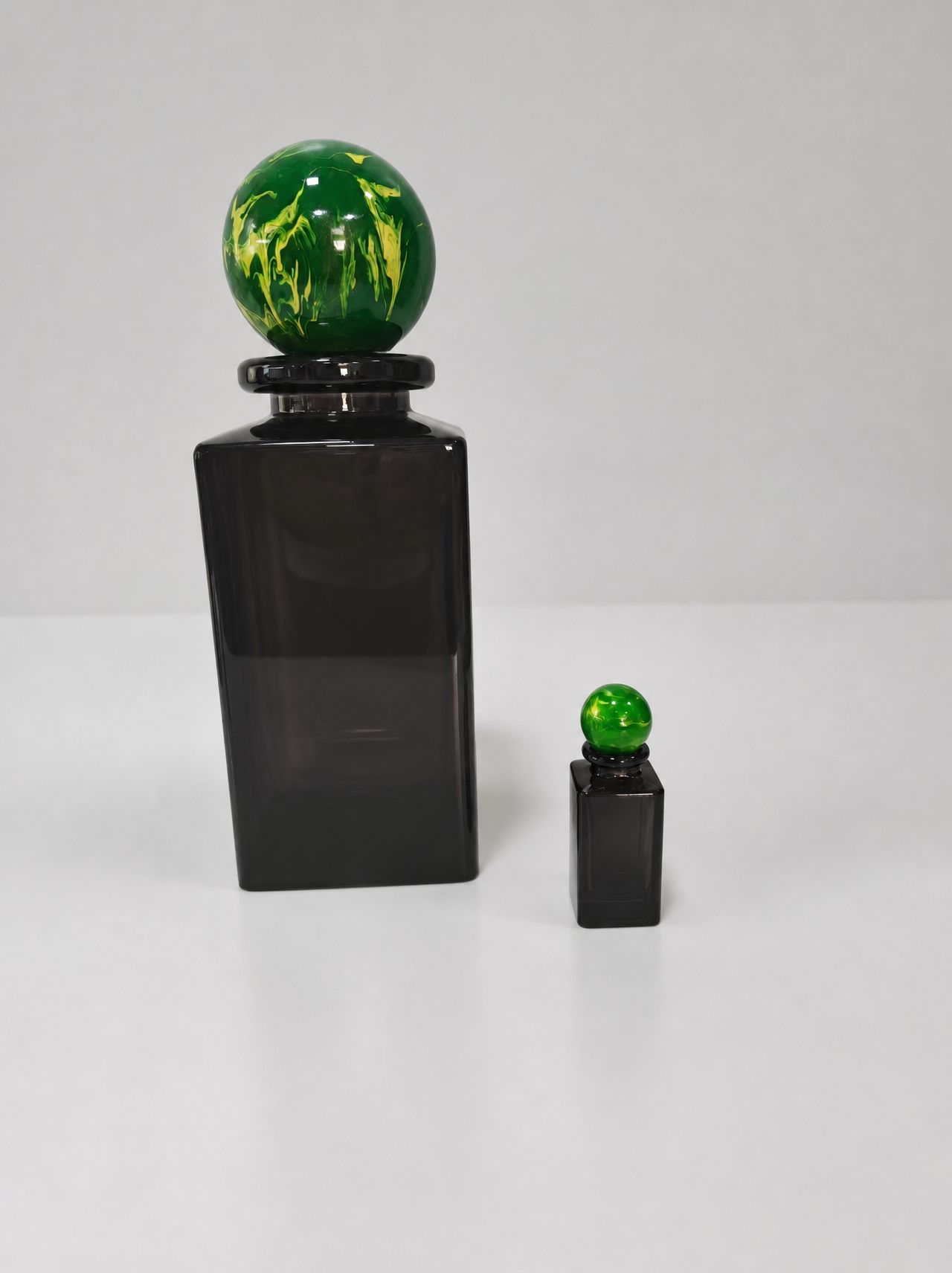 Dark brown translucent glass perfume bottle display models with green and yellow marble-pattern spherical caps