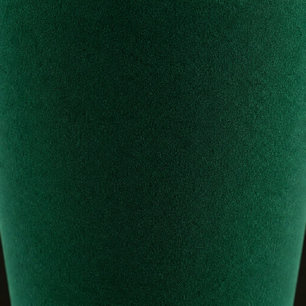 Close-up macro of the deep emerald green velvet flocked surface of a factice perfume bottle, showing the short upright pile