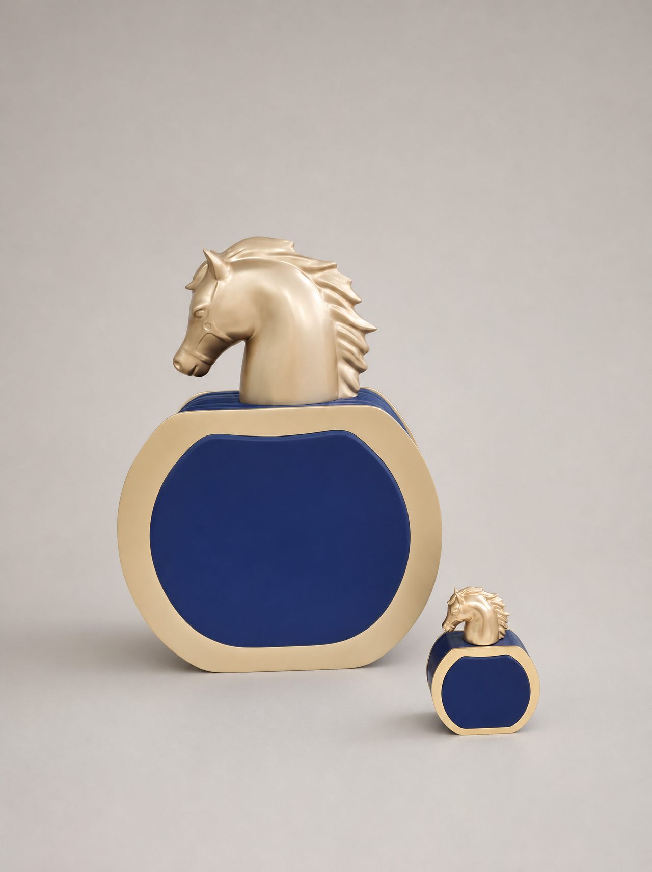 Matched pair of blue and gold perfume bottle display models with sculpted gold horse-head caps on a studio background