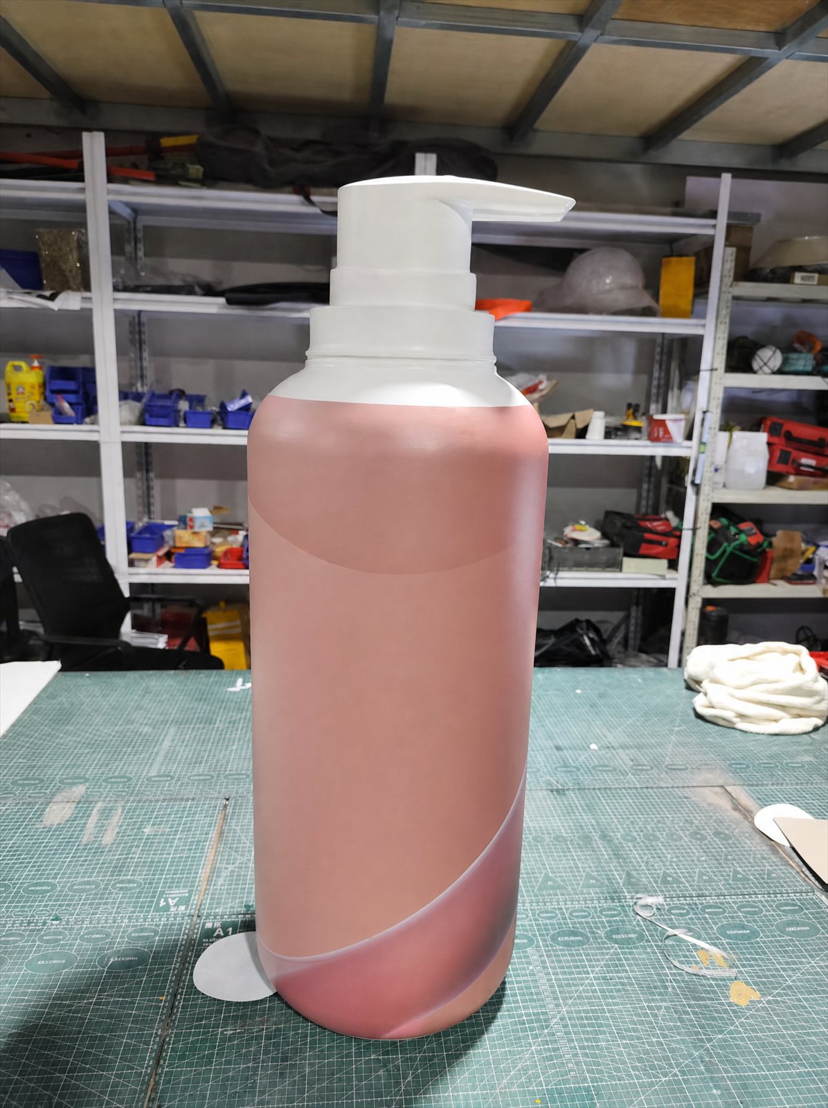 0.92 m giant dummy body lotion bottle display model in matte terracotta and rose fiberglass, standing on a cutting mat in the workshop